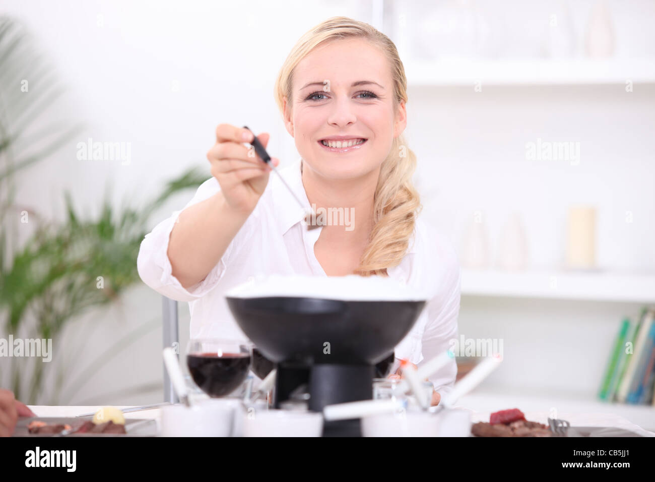 Frau, die ein Fondue bourguignonne Stockfoto