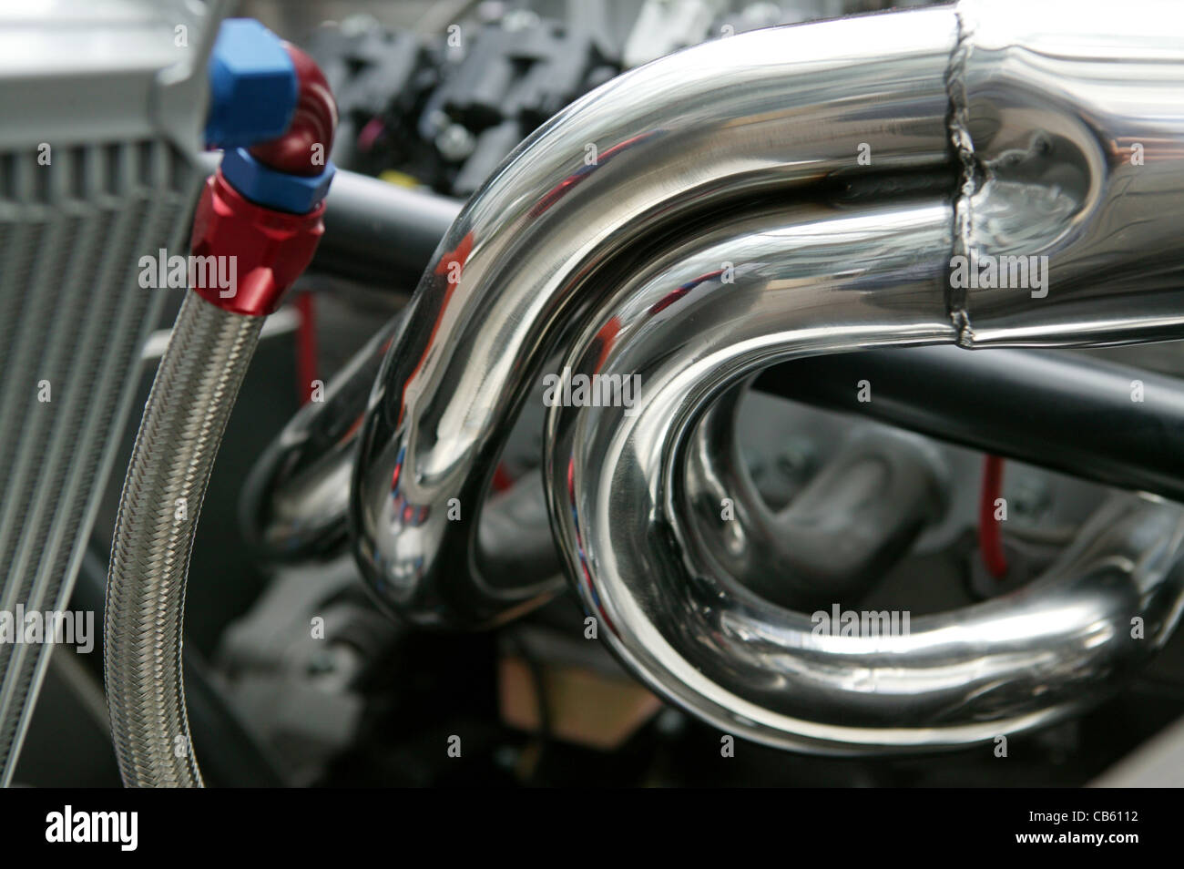 Chrom-Abgaskrümmer auf einem 4-Zylinder-Motor mit Reflexionen und Details. Stockfoto