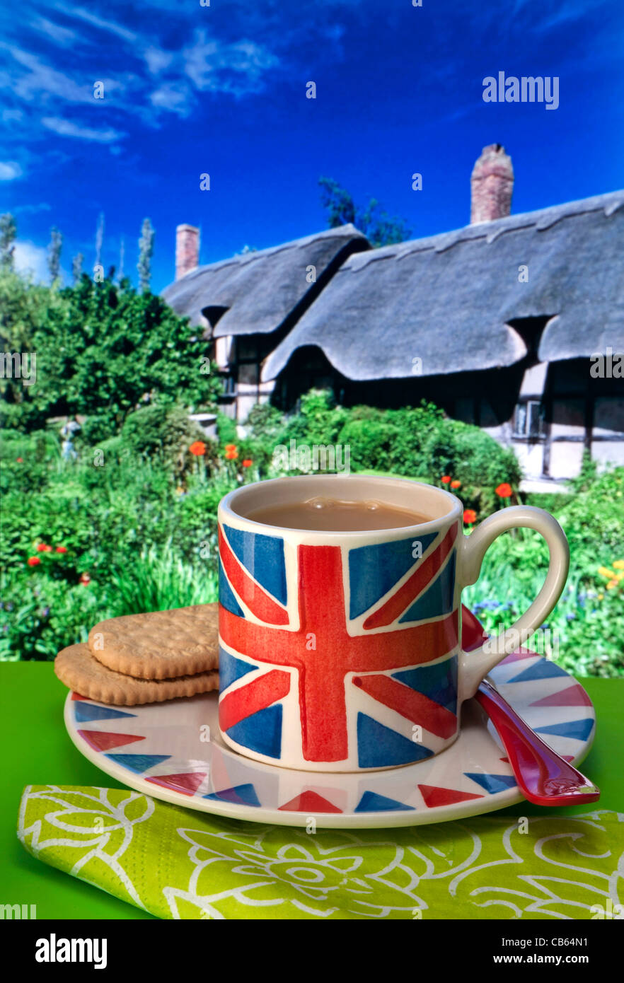 Englischer Tee Union Jack Flagge themed Tasse Tee und Kekse, typische Reetdachhäuser und Garten im Hintergrund UK Stockfoto