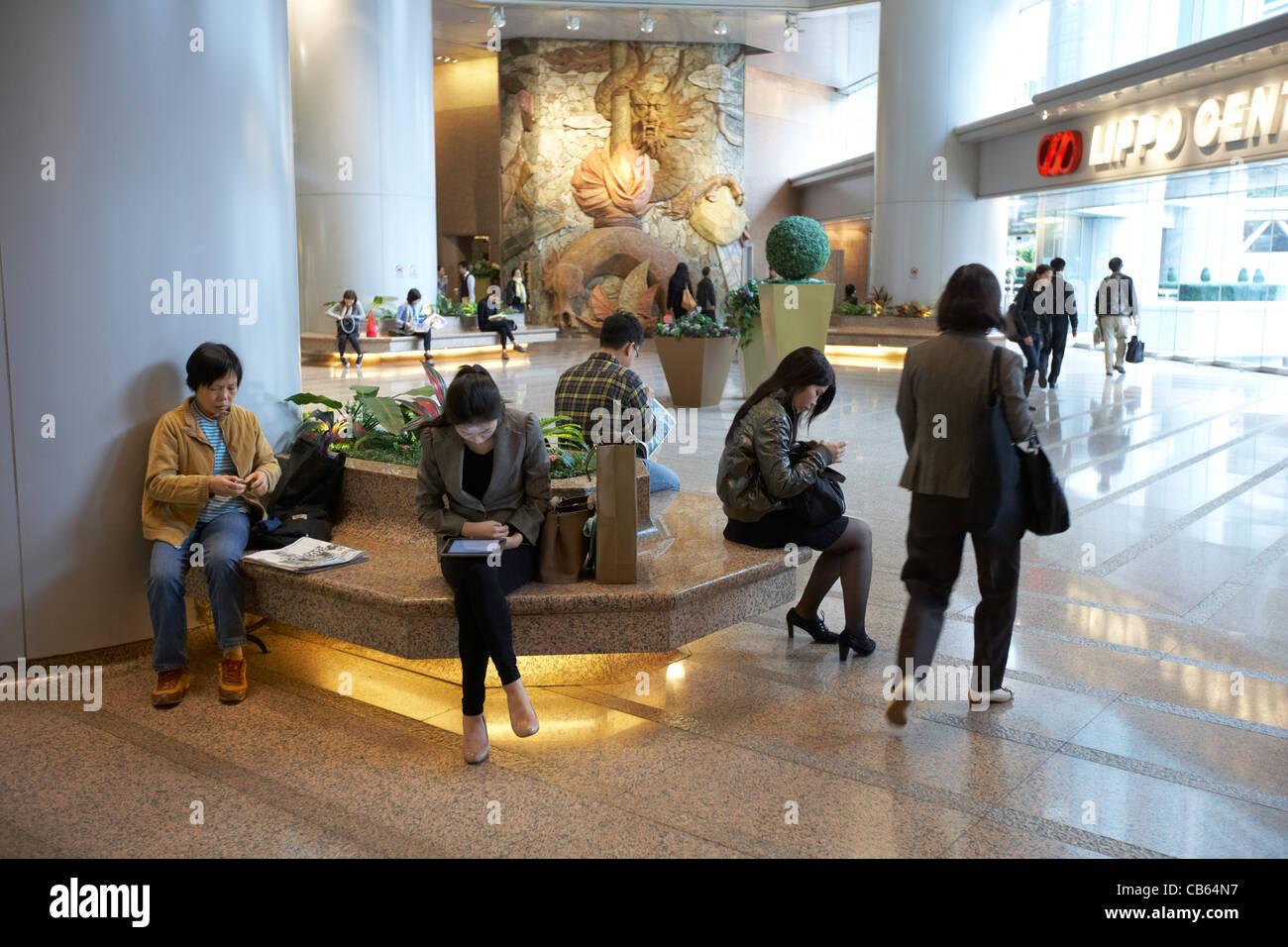 Chinesen im Foyer Atrium des Lippo Gebäudes lesen Papiere Ipads Tabletten Admiralität Bezirk, Hong Kong Insel hksar Stockfoto