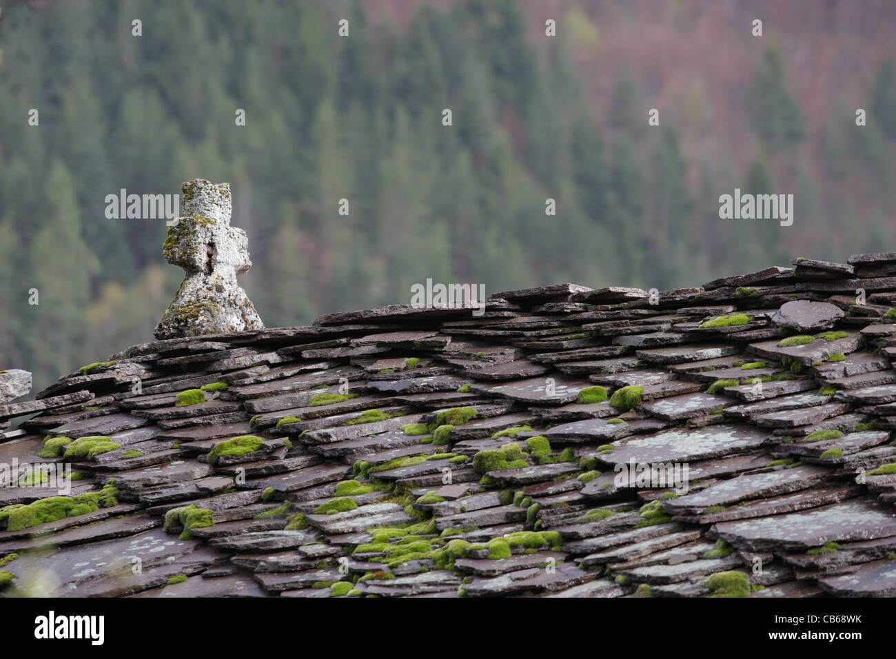 Schieferdach einer orthodoxen Kirche Kreuz. Steinfliesen mit Moos und Flechten auf Dach. Traditionelle Architektur in Bulgarien. Stockfoto