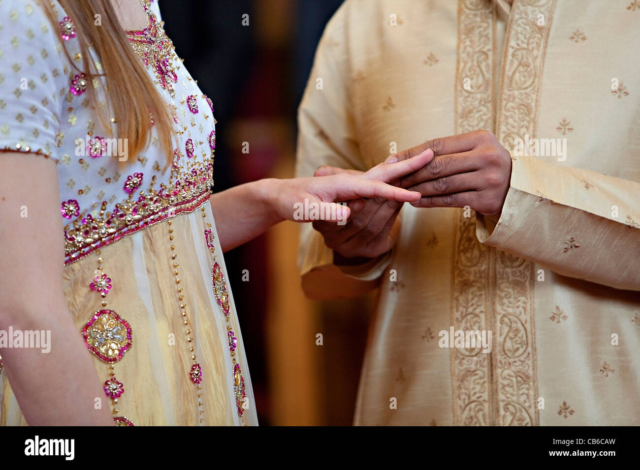 Bräutigam setzt Ehering am Ringfinger der Braut. Stockfoto