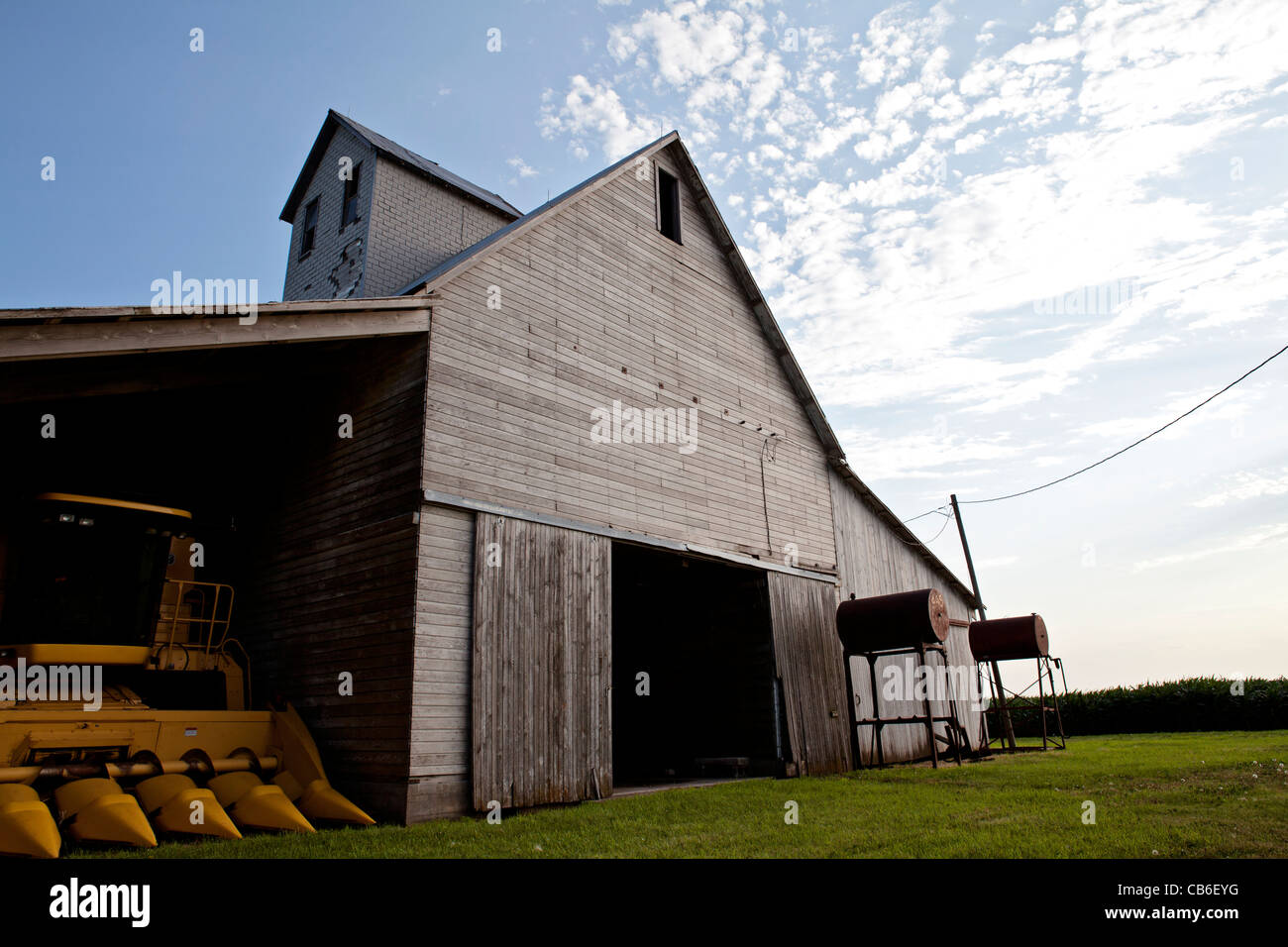 Alte Scheune auf Bauernhof mit Zapfsäulen und blauer Himmel mit Wolken. Iowa. Midwest. Kombinieren. Stockfoto