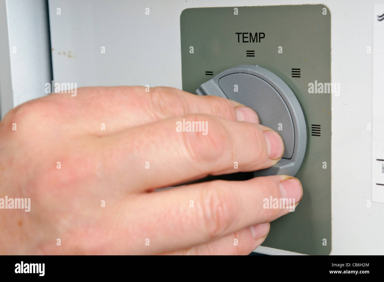 Man passt sich den Thermostat auf einem inländischen Kessel Stockfoto