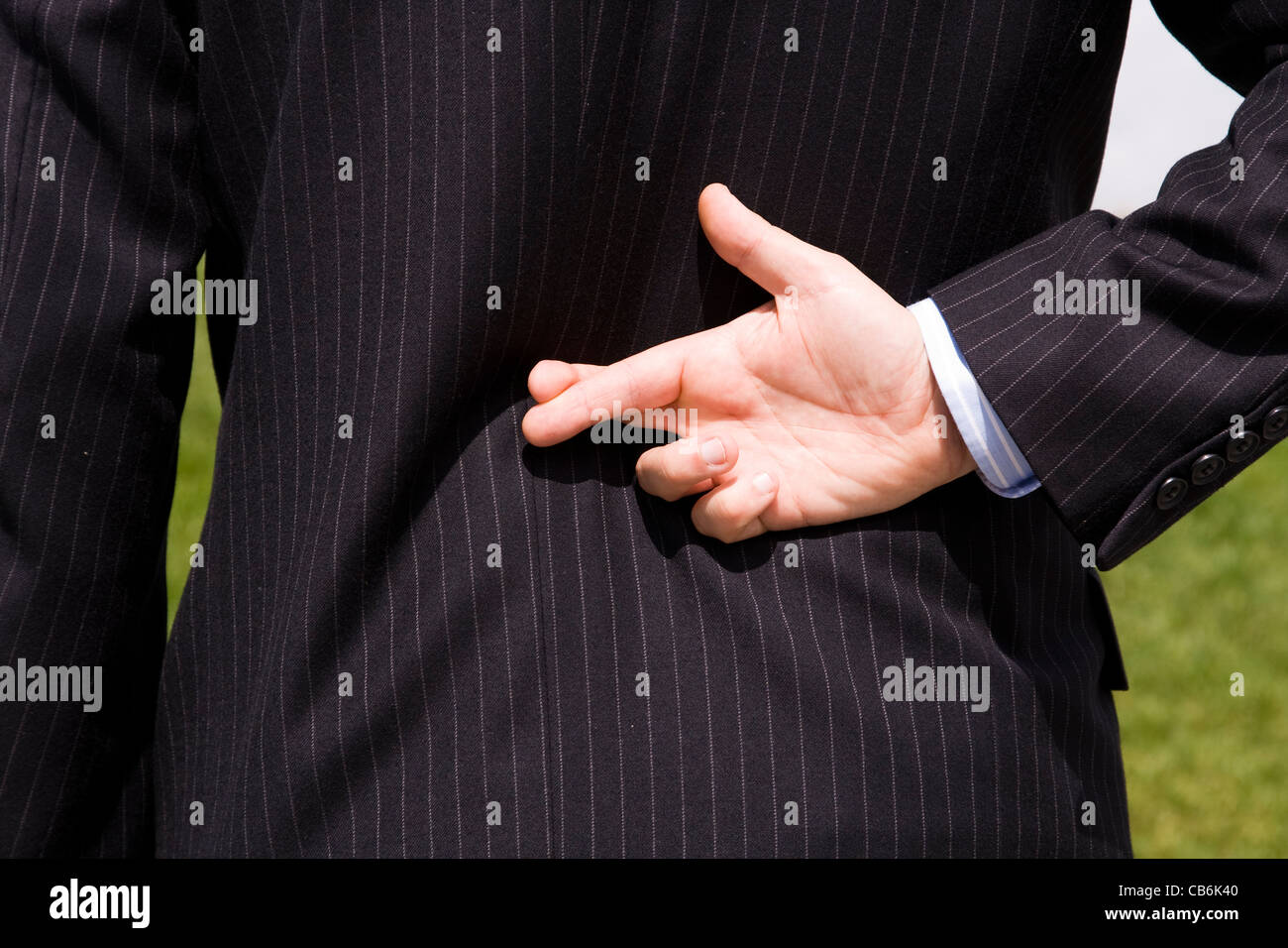 ein Geschäftsmann erzählt eine Lüge mit dem Daumen Stockfoto