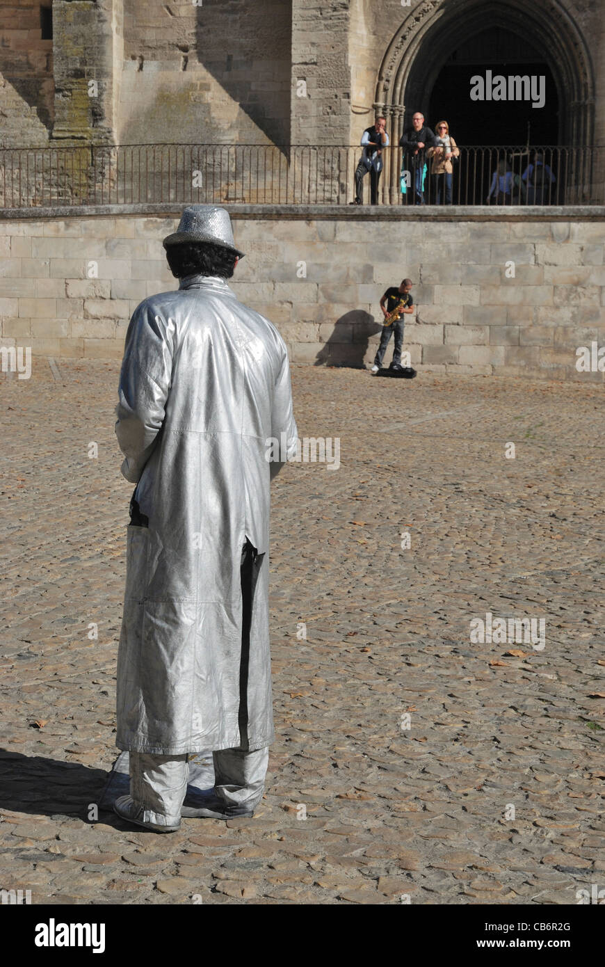 Eine lebende Statue und ein Saxophonist als Straßenmusikant vor dem Palast der Päpste, Avignon, Vaucluse, Provence, Frankreich. Stockfoto