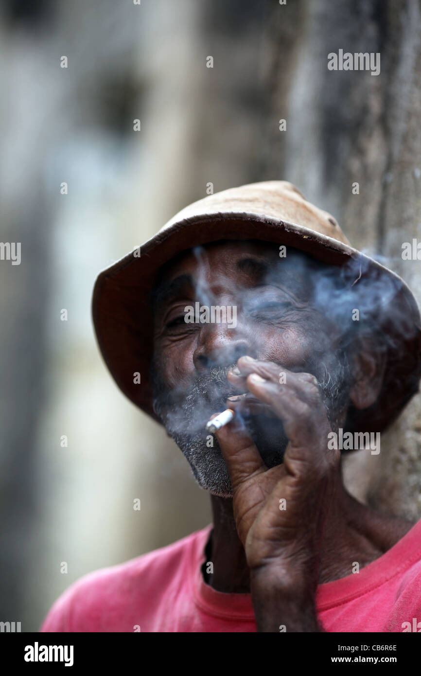 Ein madagassischen Mann in den Fünfzigern, rauchte eine Zigarette, trägt ein rosa T-shirt, in Ankify, Nordküste westlichen Madagaskar, Afrika. Stockfoto