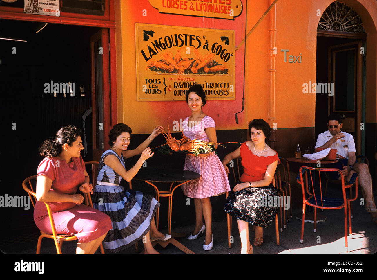 Französische Frauen der 1950er Jahre oder der 1960er Jahre vor einem Seafood-Restaurant spezialisiert auf Hummer, Porto-Vecchio, Korsika, Frankreich Stockfoto