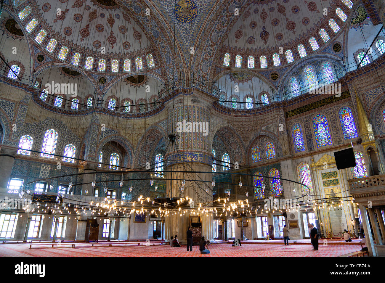 Türkei, Istanbul, Sultanahmet Camii, die blaue Moschee-Interieur mit Menschen beim Gebet unter Kronleuchtern und verzierten Kuppeln. Stockfoto