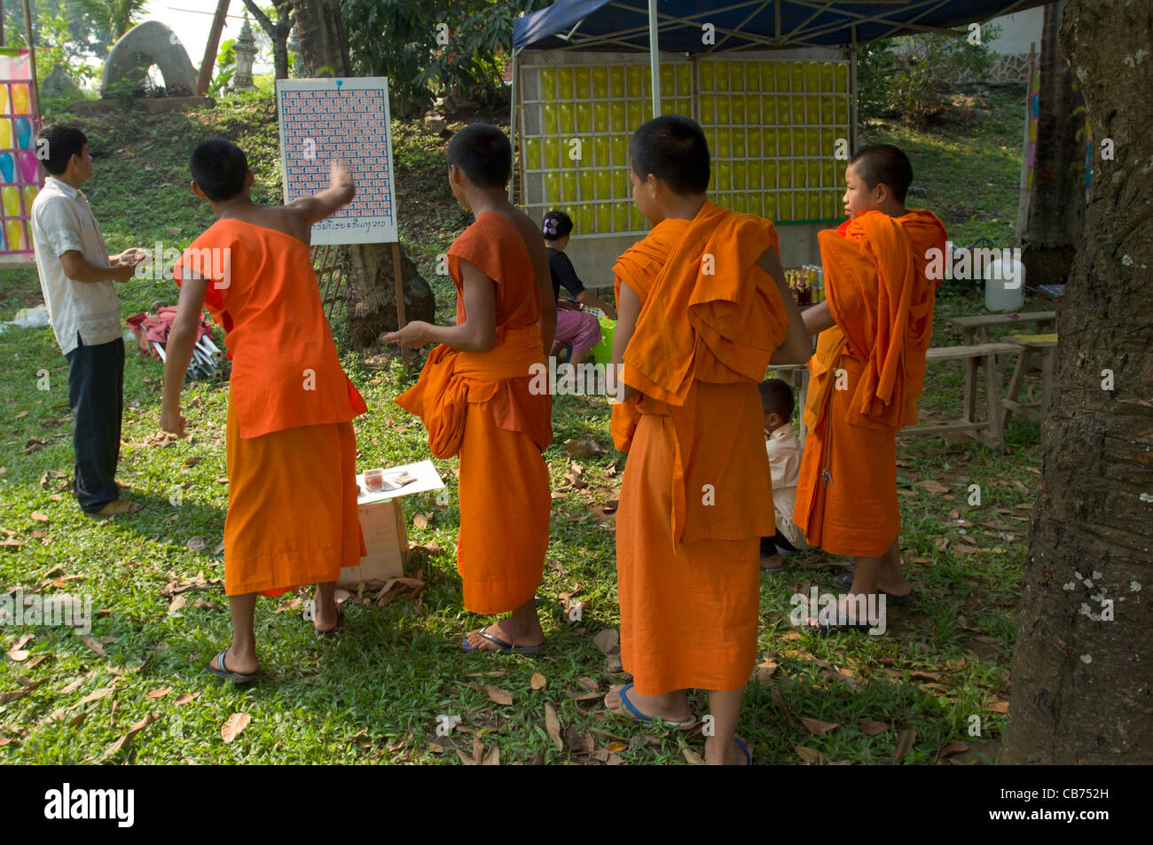 Buddhistischen Novizen werfen Darts auf ein Nebenschauplatz, Lao Neujahr (Pi Mai Lao), Luang Prabang, Laos Stockfoto