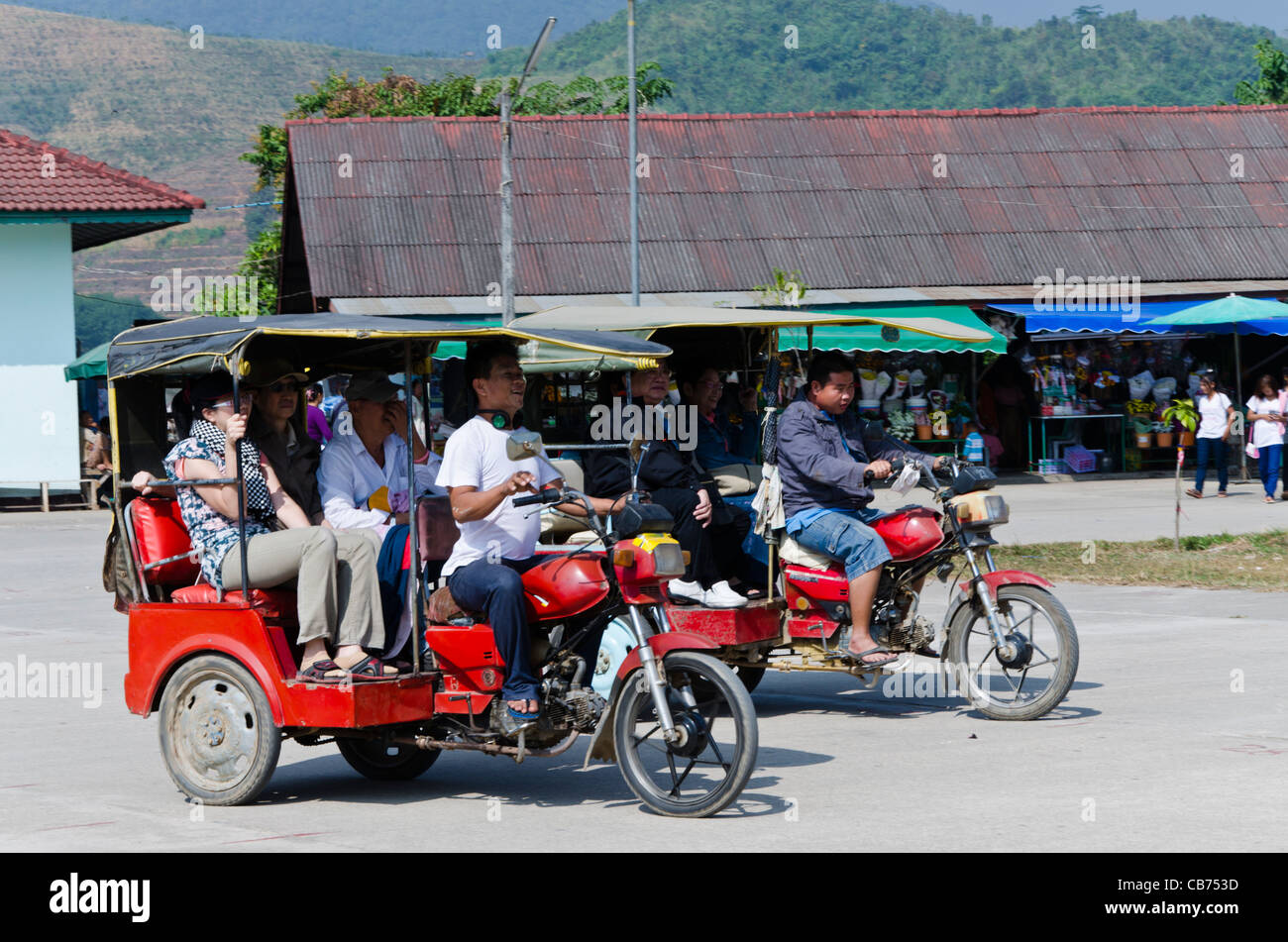Zwei burmesische Tuk-Tuks mit lachenden Touristen & Fahrer treten gegeneinander in Tachileik Shwe Dagon Pagode in Tachileik Myanmar Stockfoto