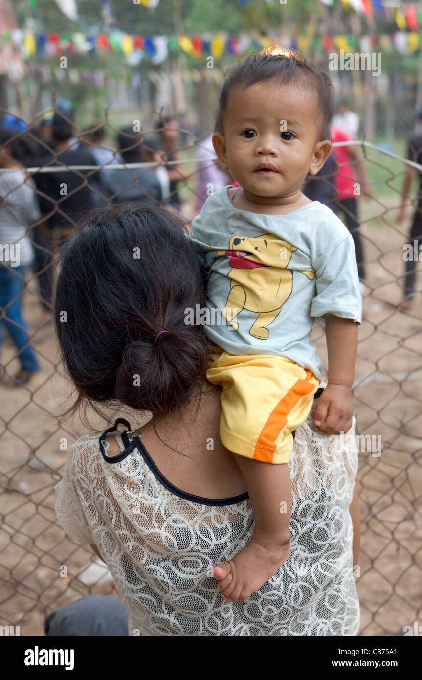 Kleines Kind sitzt auf der Schulter seiner Mutter bei einem Dorffest, kambodschanischen Neujahr (Chaul Chnam Thmey), Bakong Dorf, Siem Reap, Kambodscha Stockfoto