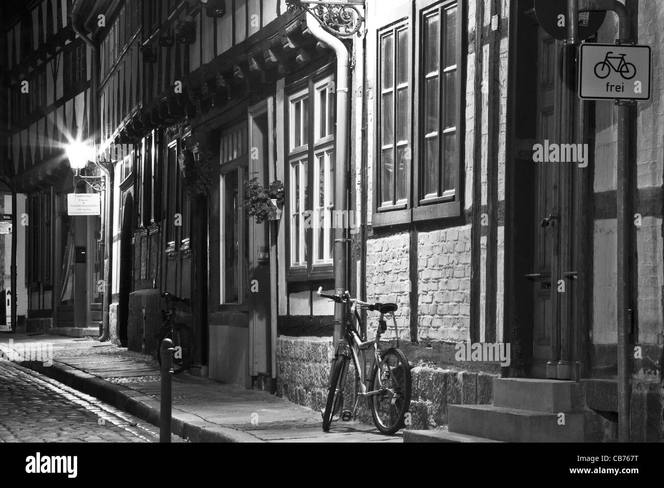 Einer schmalen gepflasterten Straße umrahmt Holzhäuser und ein Fahrrad in der Nacht in Quedlinburg, Deutschland.  Farb-Version zur Verfügung: CB77HC Stockfoto