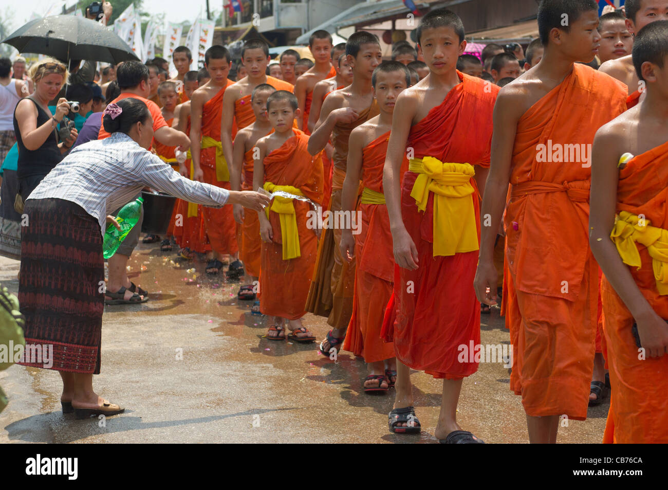 Buddhistische Mönche in einer Prozession mit Wasser auf sie geworfen für einen Segen auf Mue Nau, den mittlere Tag der Lao Neujahr (Pi Mai Lao), Luang Prabang, Laos Stockfoto