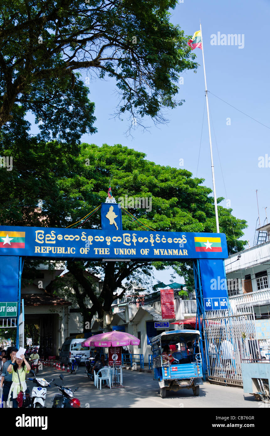 Neue "Republik der Union von Myanmar" Schild am Grenzübergang in Tachileik Myanmar mit Fahnen, Fußgänger, Wachen & Tuk tuk Stockfoto