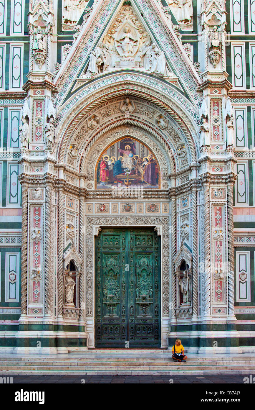 Touristen sitzen neben den massiven Vordertüren nach Dom - Santa Maria del Fiore, Florenz Toskana Italien Stockfoto