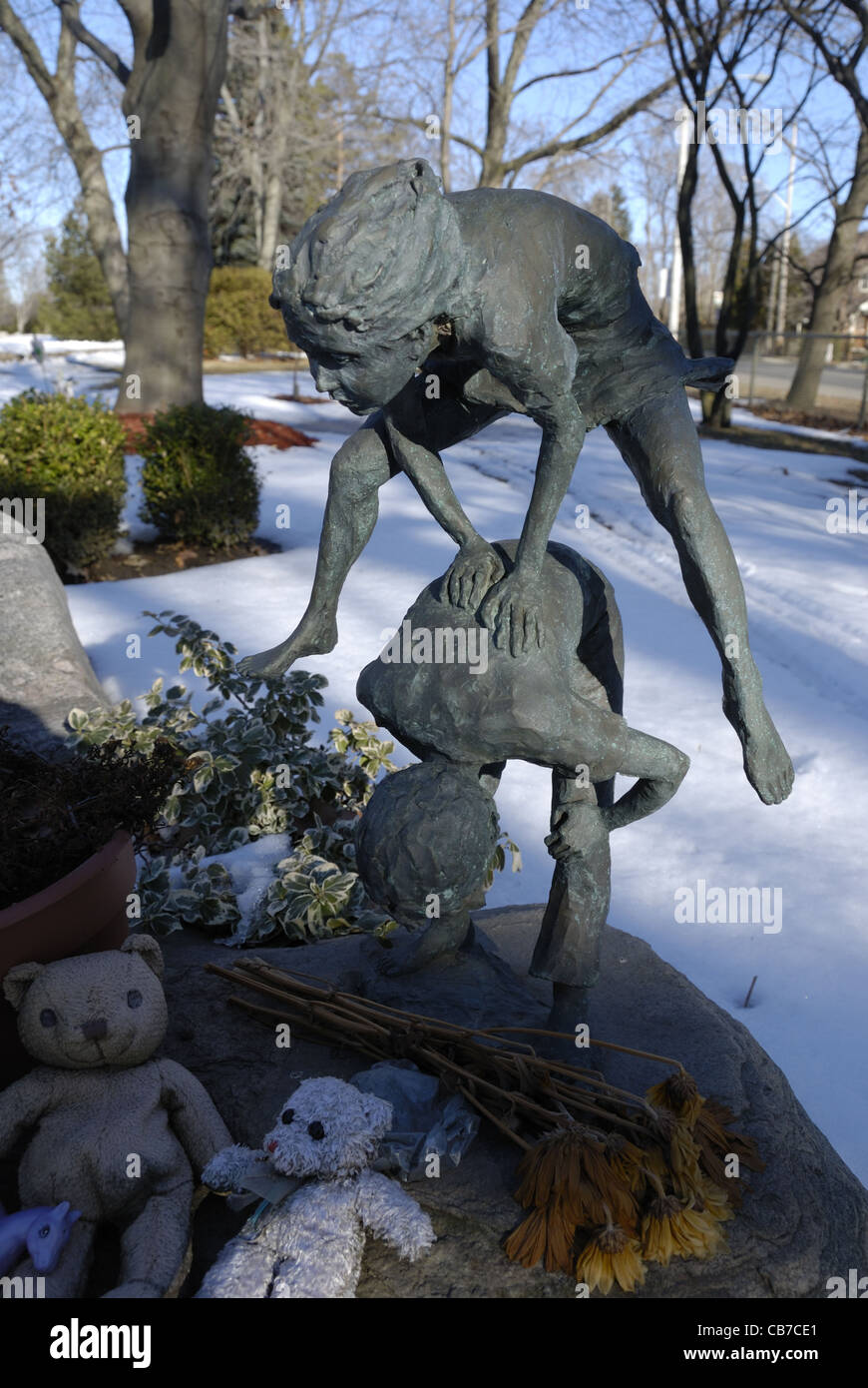 Eine einzigartige Bronze-Gedenkskulptur an einem Kindergrab, die Kinder zeigt, die Springfrosch spielen Stockfoto