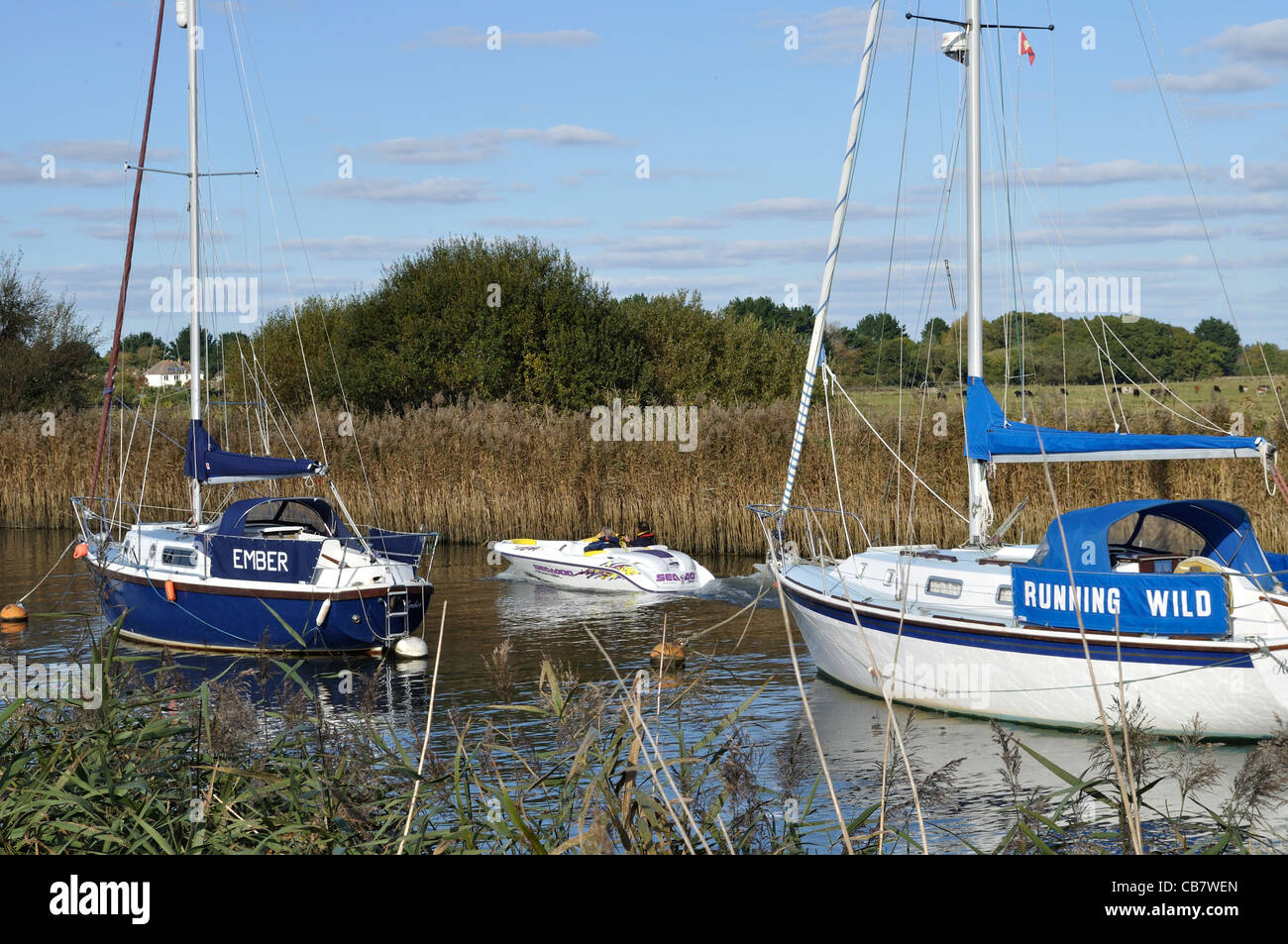 Yachten Ember ein Running Wild vor Anker am Fluß Frome, in der Nähe von Wareham, Dorset, mit Motorboot zwischen. Stockfoto