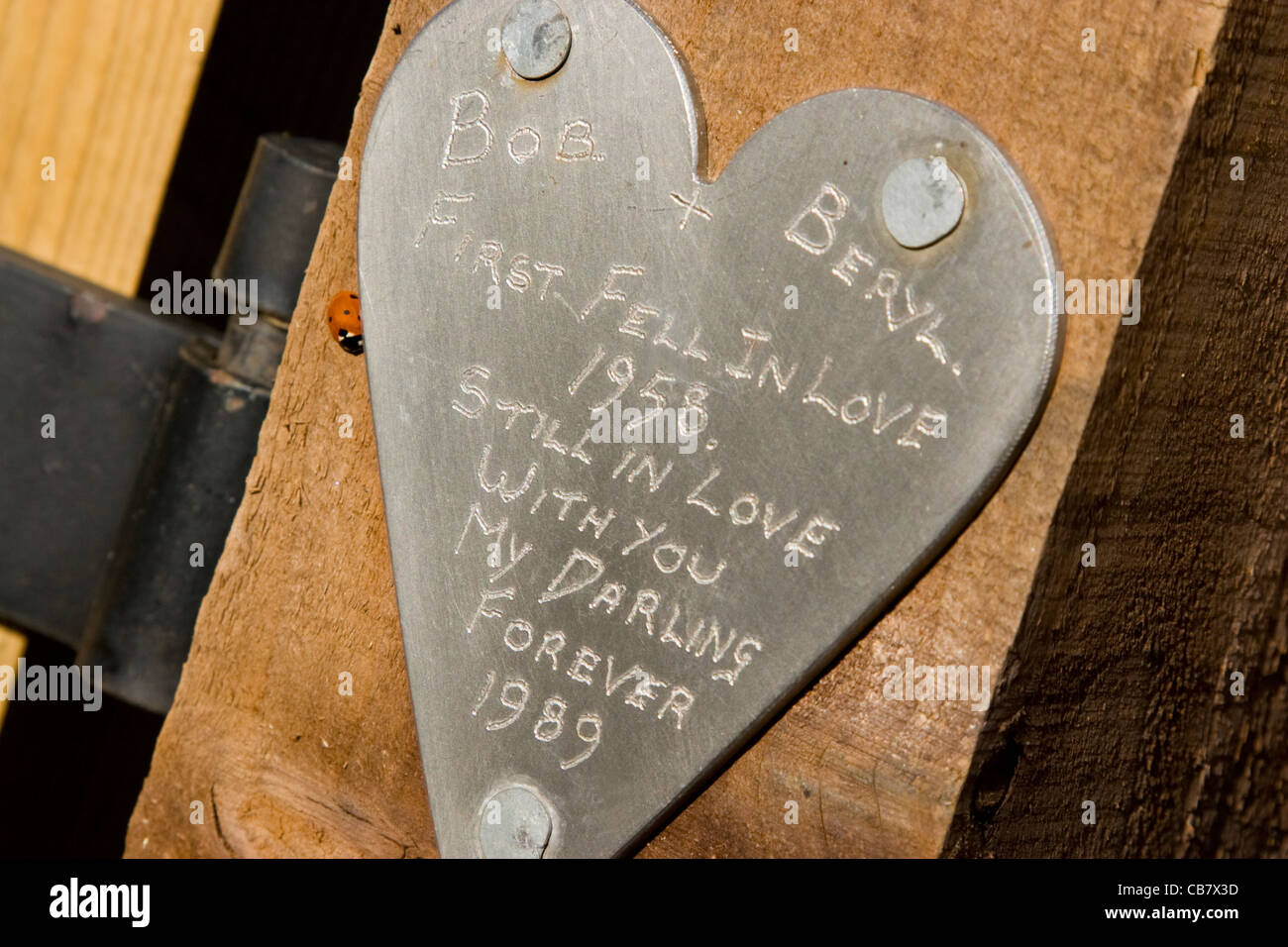 Eine persönliche Liebesbotschaft eingraviert auf eine herzförmige Plakette an einem Wanderweg Pfosten befestigt Stockfoto