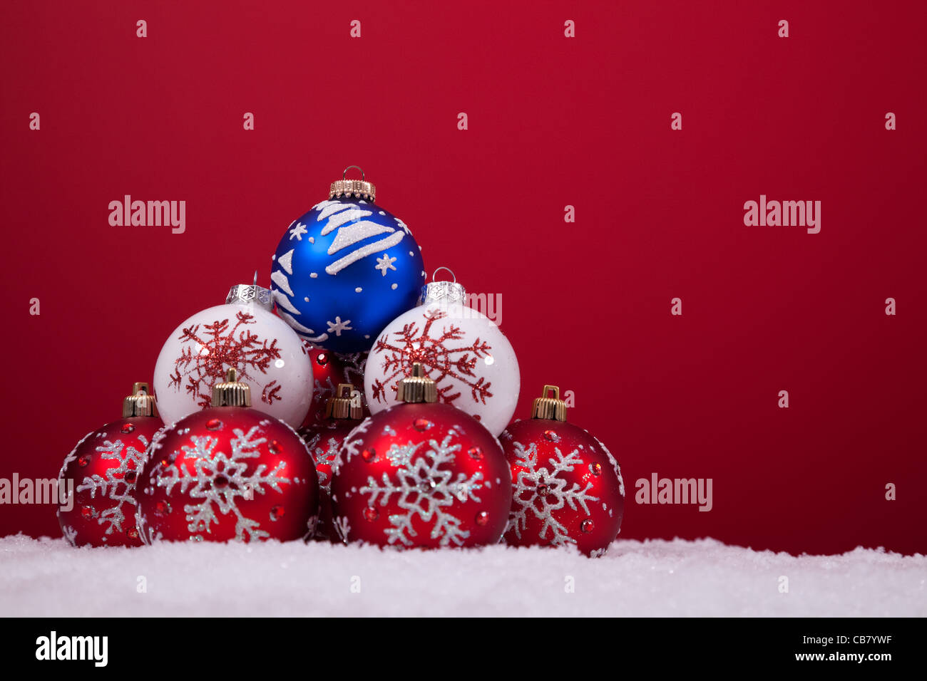 bunte Weihnachtskugeln über den Schnee mit einem roten Hintergrund (Tiefenschärfe) Stockfoto