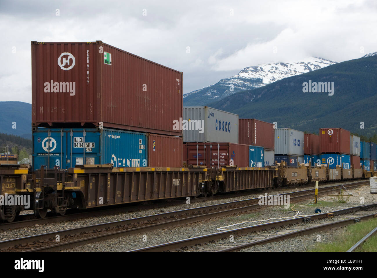 Container auf Zug, Jasper, Alberta, Kanada, Rocky Mountains in Ferne. Stockfoto