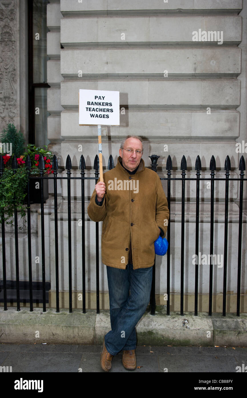Mann steht neben Geländer halten ein Plakat darauf hindeutet, dass Banker versuchen auf Lehrer Lohn Leben allein. Stockfoto