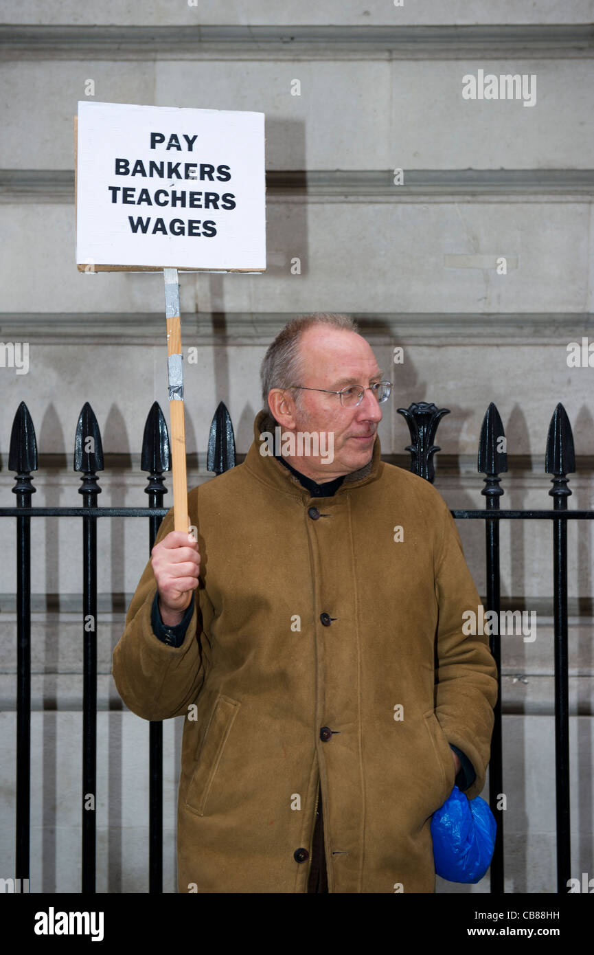 Mann steht neben Geländer halten ein Plakat darauf hindeutet, dass Banker versuchen auf Lehrer Lohn Leben allein. Stockfoto