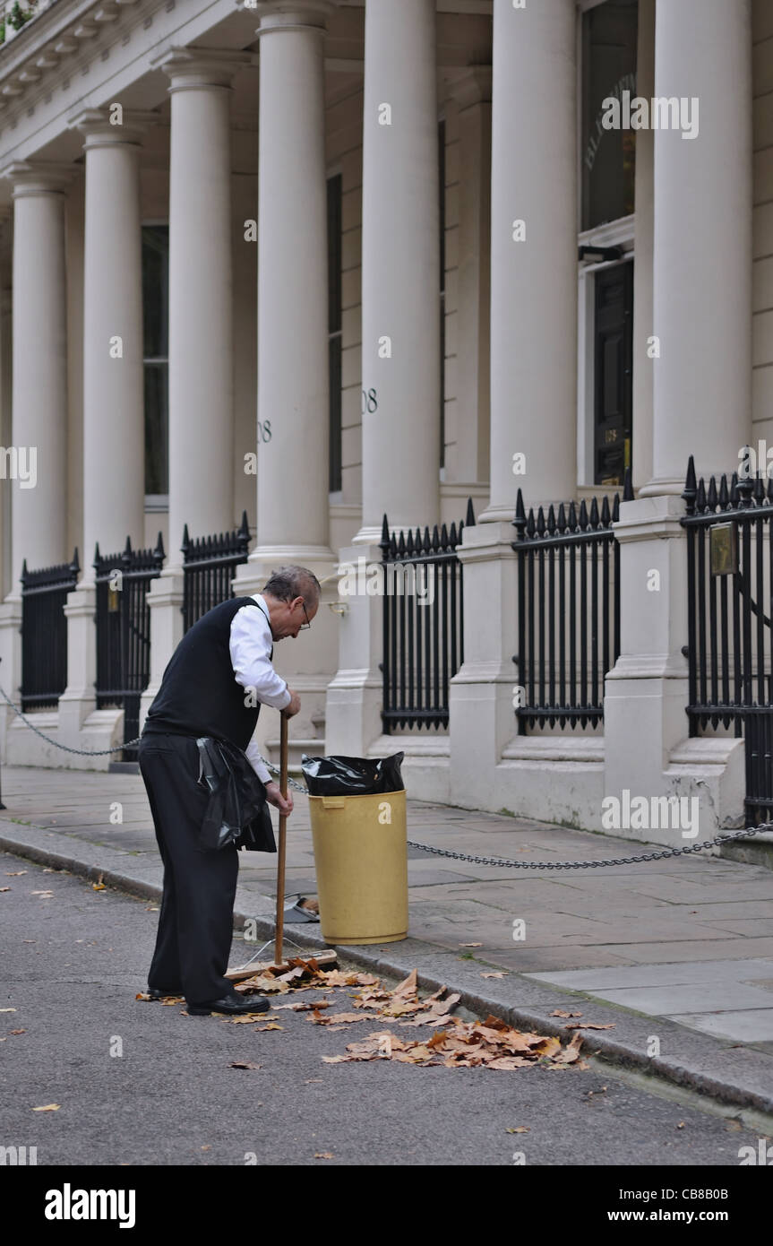 London: Mann mit Besen fegen Laub Stockfoto