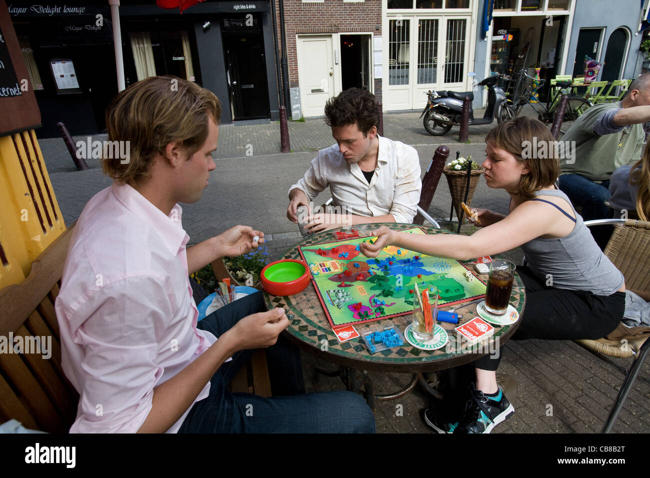 Junge Gruppe spielen Risiko in einem Straßencafé, Amsterdam, Niederlande Stockfoto