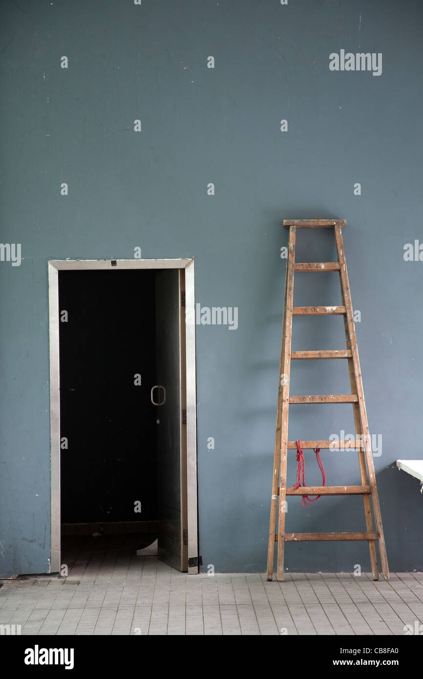 Leiter gelehnt neu lackiert dunkel graue Wand in der Nähe einer offenen Tür Hong Kong Island, SAR China Stockfoto