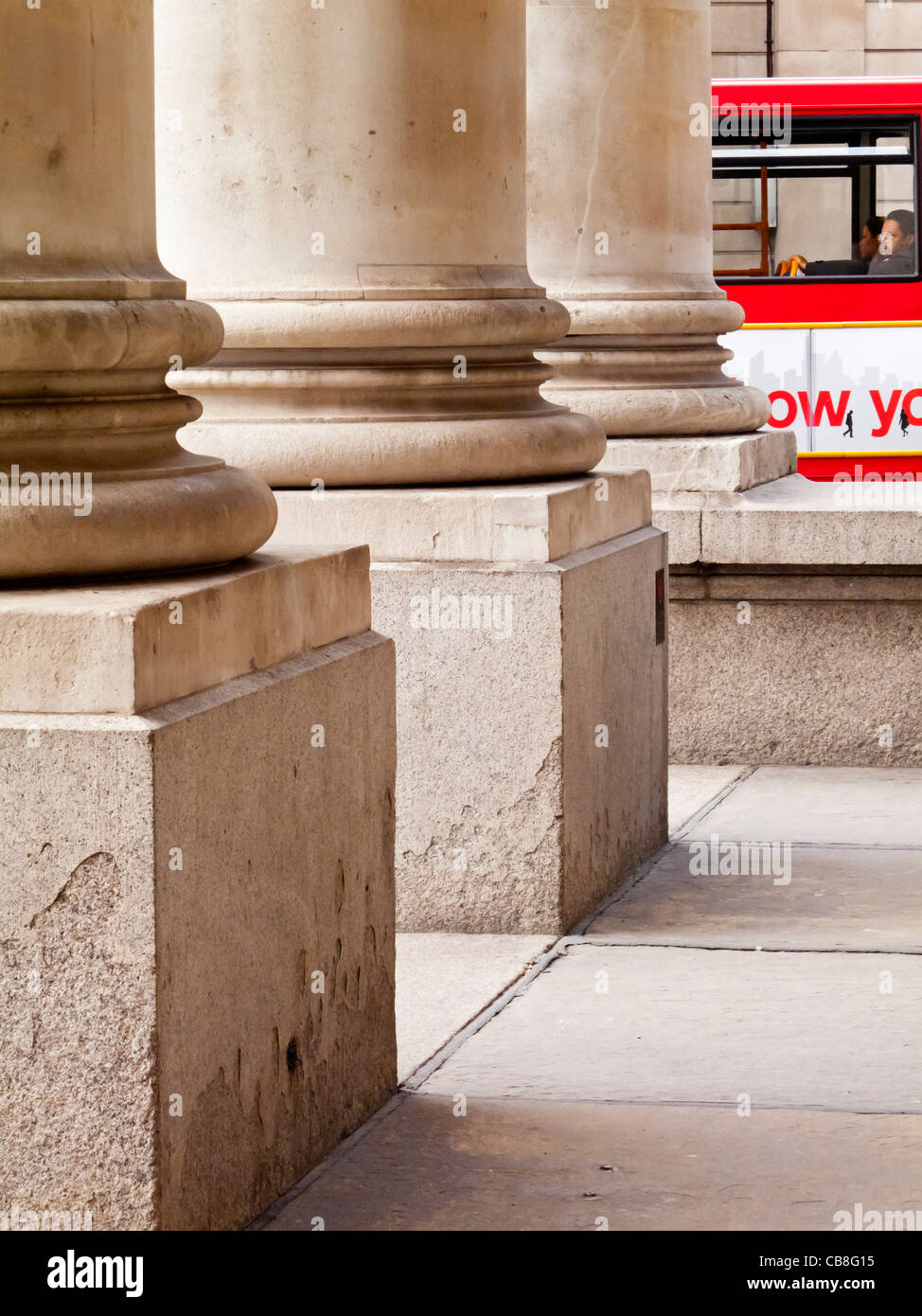 Detail der steinernen Säulen am Eingang zum Royal Exchange Building in London England UK mit roten Bus in Ferne Stockfoto