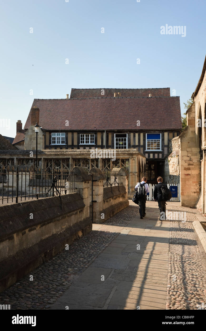 Schüler, die das kleine Tuchmacherhaus der Königsschule auf dem Domplatz betreten. Gloucester Gloucestershire England Großbritannien Stockfoto