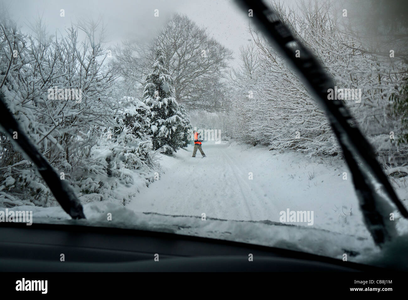 Treiber anzeigen durch Auto Windschutzscheibe ländlichen Lane in starkem Schneefall mit Kreuzung in Warnschutz Jacke Mann Stockfoto