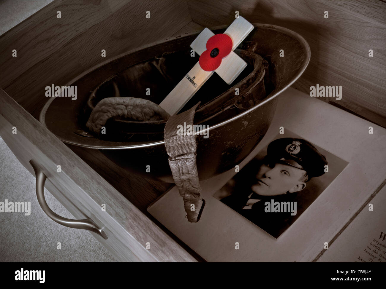 WW2 Helm in einer Unentschieden gehalten mit Erinnerung Tag Mohn Kreuz und alten Kriegsfoto als evokative Erinnerung an einen geliebten Menschen Stockfoto