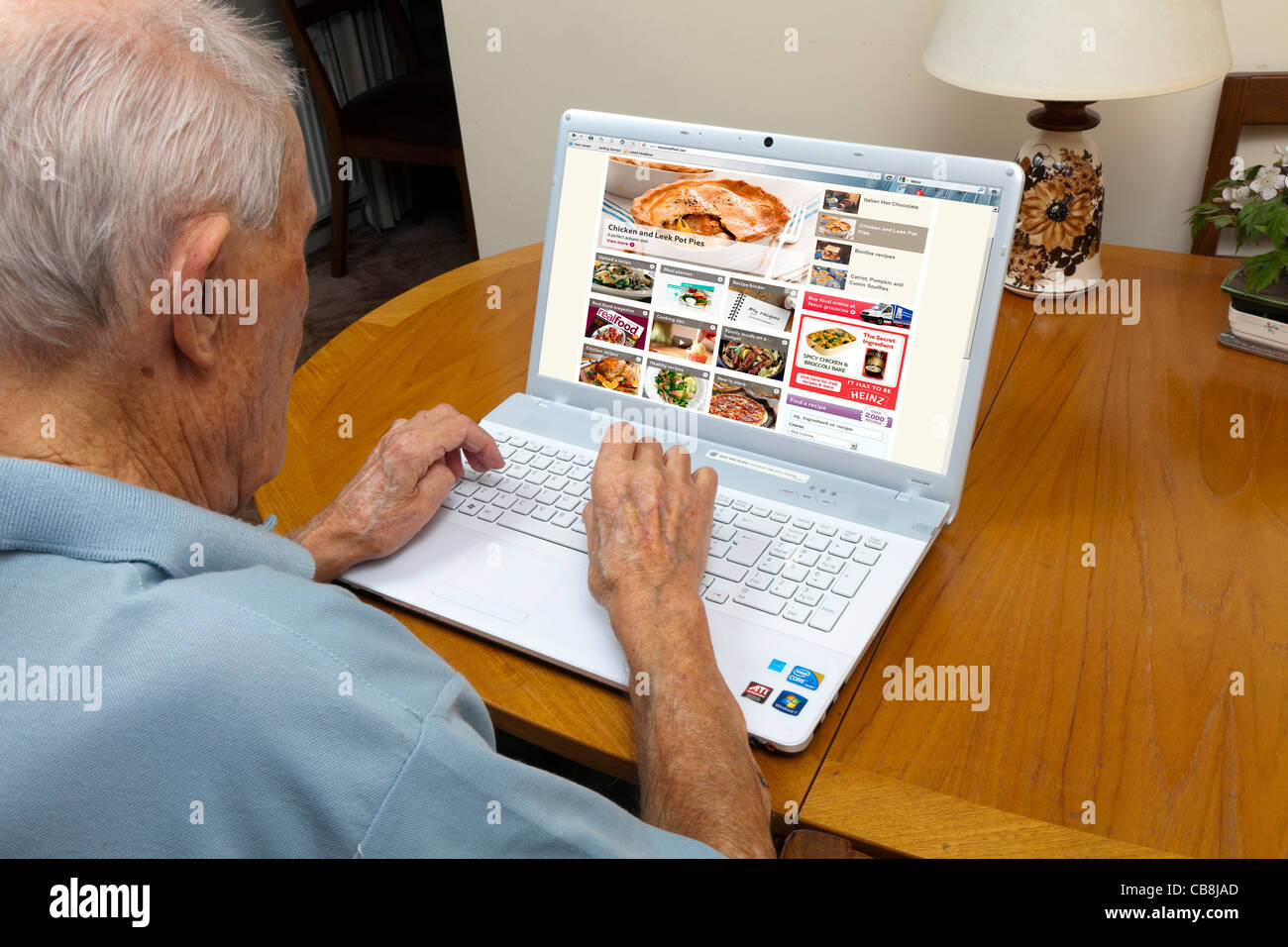 Älterer Herr, der das Surfen im Internet auf der Suche nach Ideen auf einem Laptop zu kochen Stockfoto