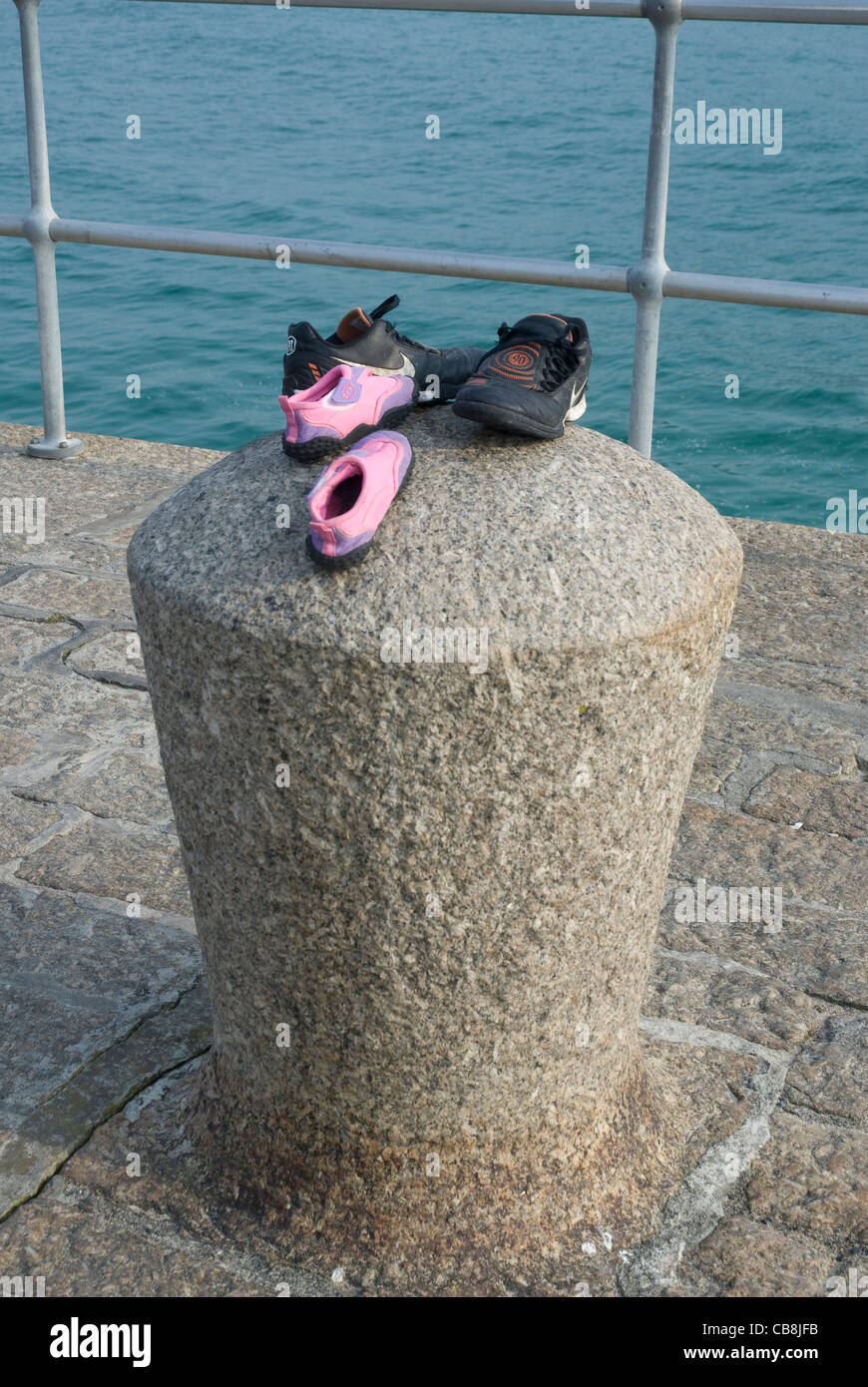 Zwei paar Kinder Schuhe links auf einem Poller am Ende des Piers, St. Ives, Cornwall, England UK Stockfoto