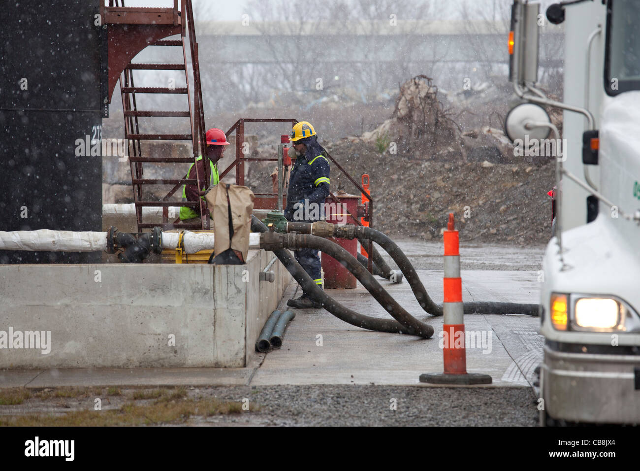 Arbeiter entladen hydraulisch Fertigung (Fracking) Flüssigkeiten aus einem Tankwagen bei einer Injektion gut Stockfoto