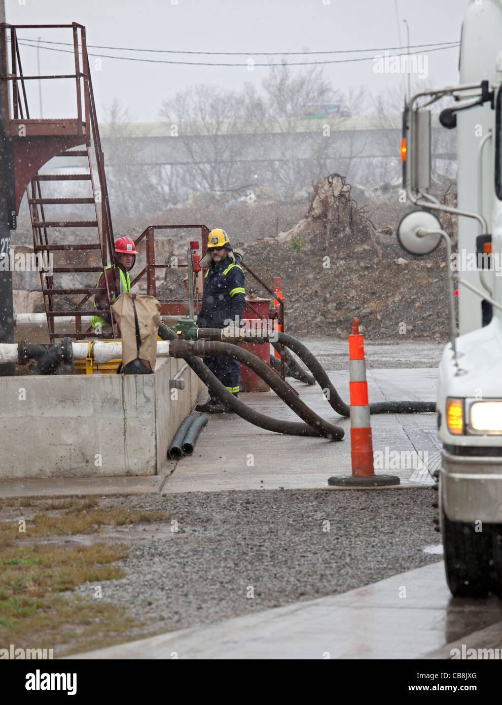 Arbeiter entladen hydraulisch Fertigung (Fracking) Flüssigkeiten aus einem Tankwagen bei einer Injektion gut Stockfoto
