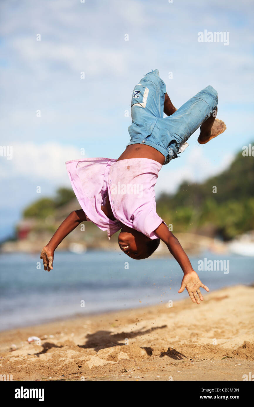 Ein Junge in der Luft ist einen wieder Flip Salto am Strand in Ampangorinana, Nosy Komba, nordwestlichen Madagaskar, Afrika Stockfoto