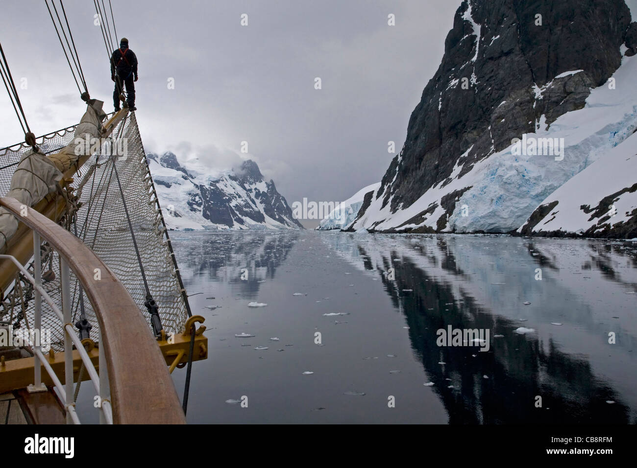 Segelschiff mit Mann am Bugspriet Blick in den Lemaire-Kanal / Kodak Gap, Antarktis Stockfoto