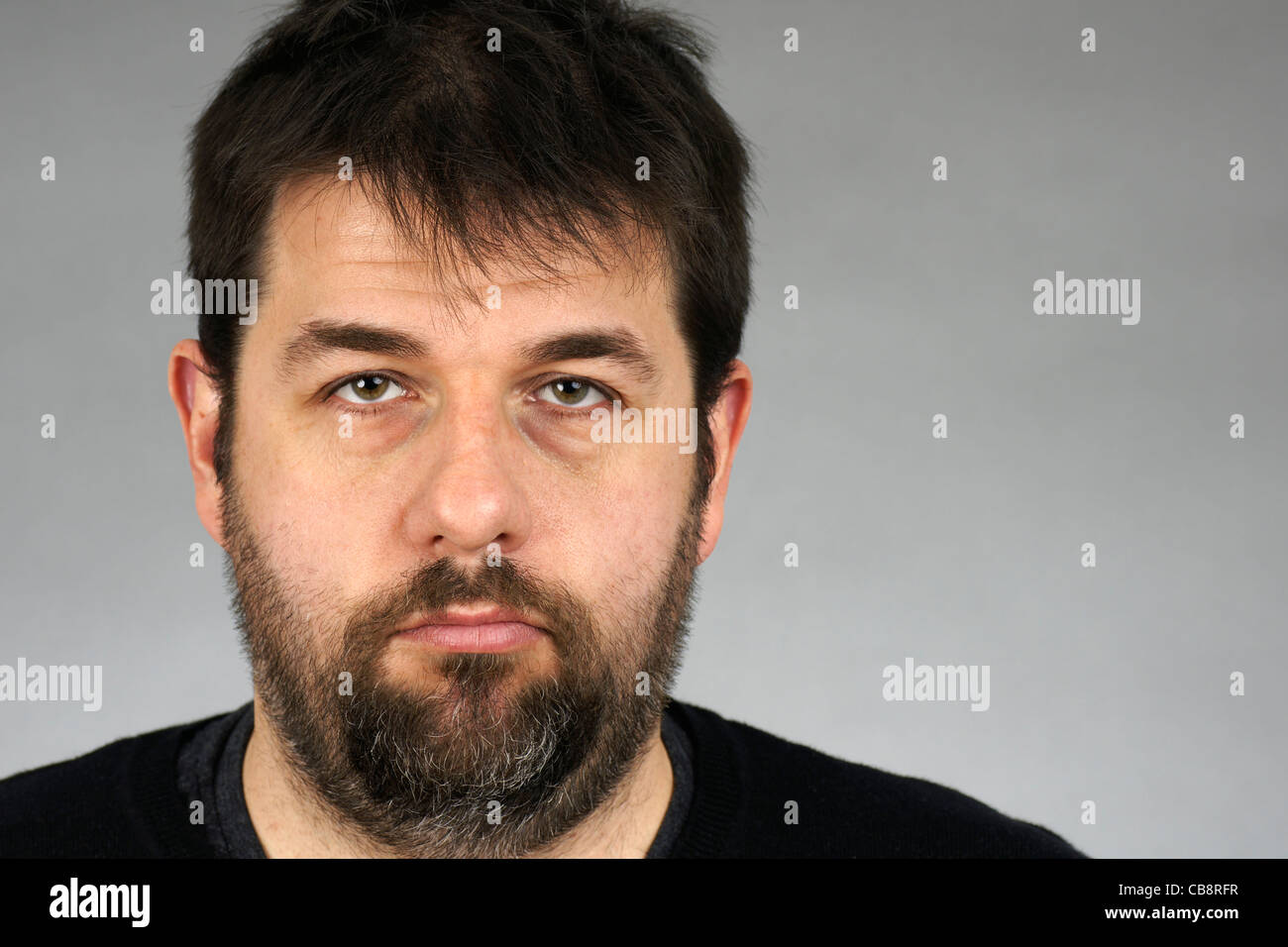 Porträt eines sehr ernsten, düsteren oder deprimiert dunkle Haare und Bart Mittleralter auf grauem Hintergrund. Stockfoto