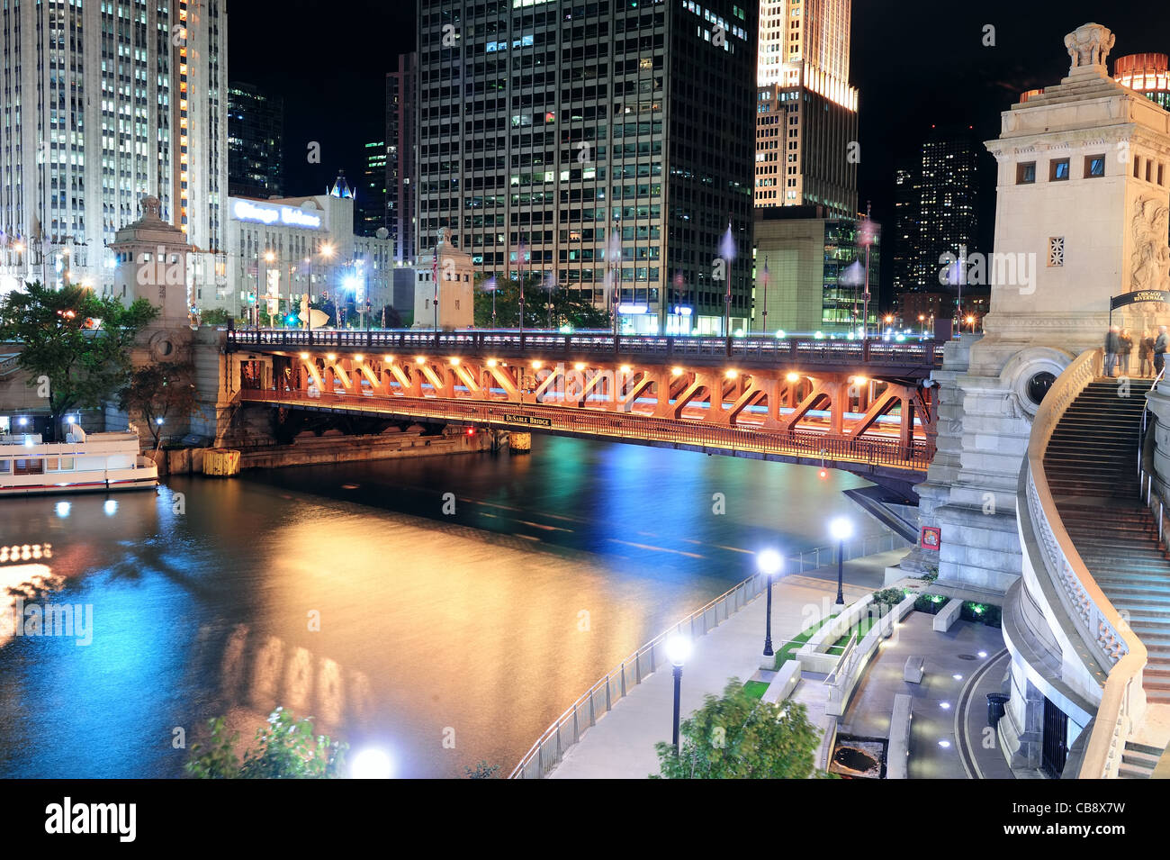 Chicago River Walk mit städtischen Wolkenkratzern und Brücke mit Licht und Wasser Spiegelung bei Nacht beleuchtet. Stockfoto