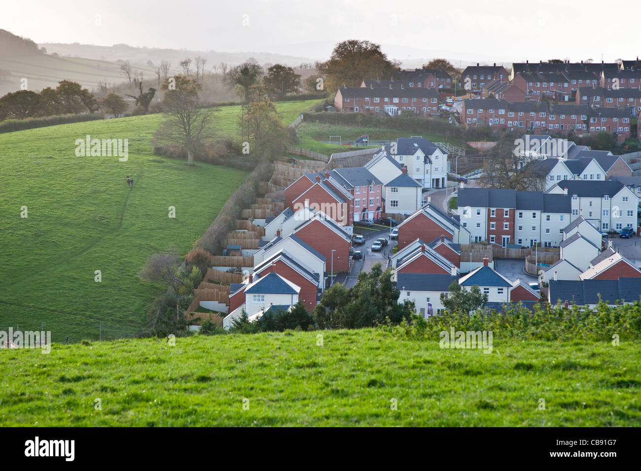 Neue Häuser erbaut auf dem Gelände einer alten Obstplantage neben den offenen Feldern in Crediton, Devon, England Stockfoto