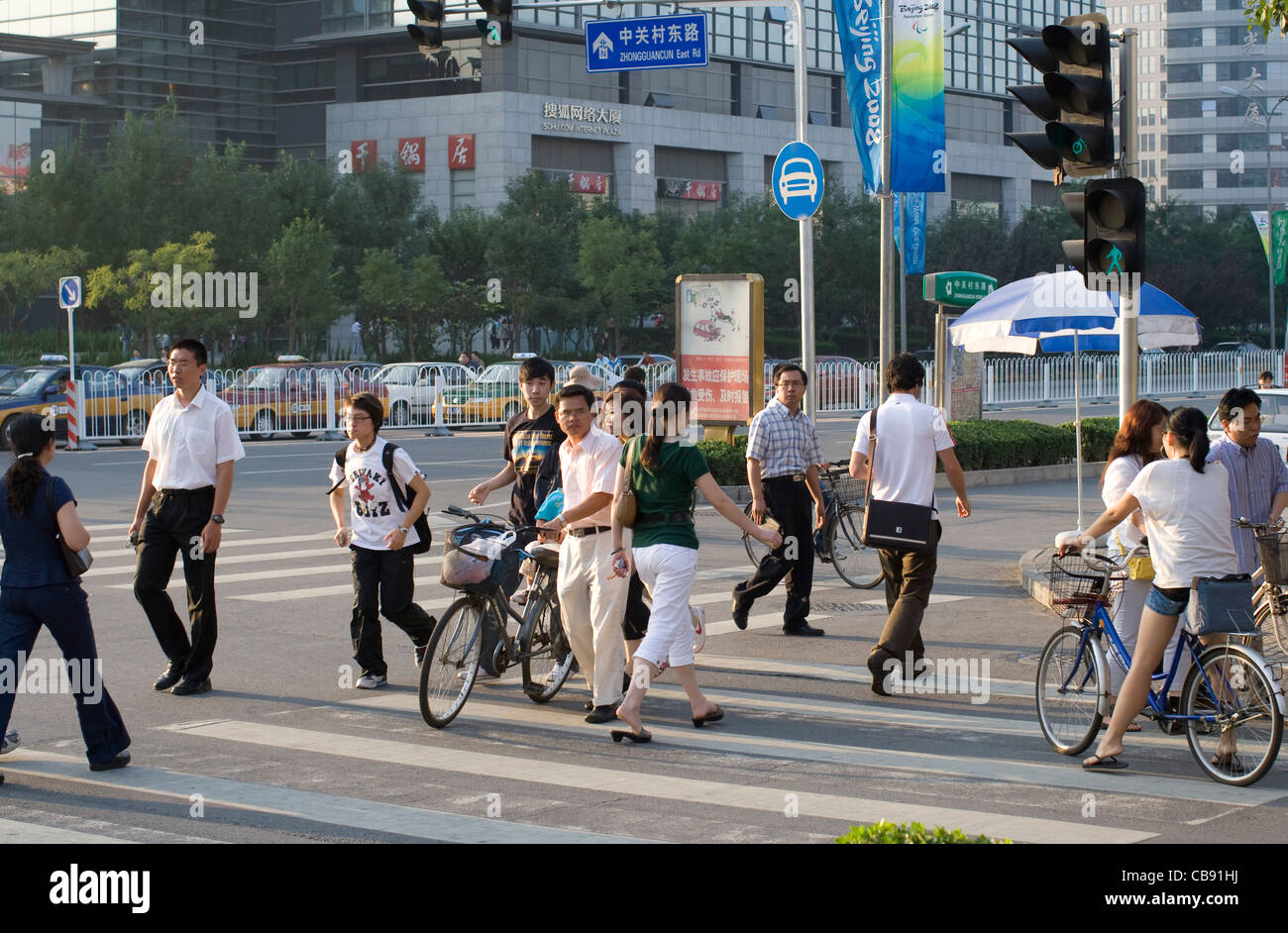 Radfahrer und Fußgänger überqueren an einem Zebrastreifen in ein beschäftigt kommerziellen Bezirk von Peking, China. Stockfoto