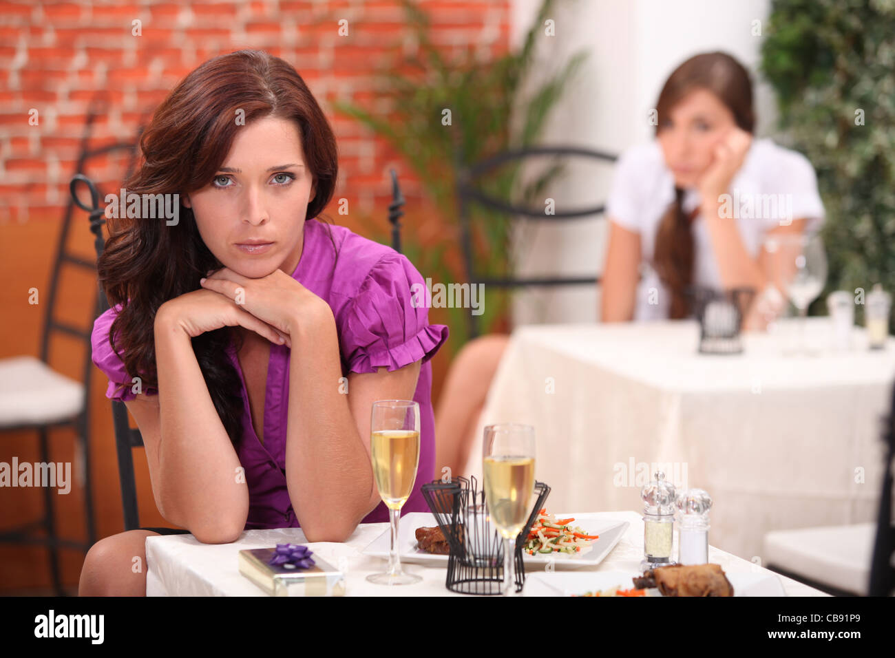 böse Frau im Restaurant, auf dem Tisch, ein ungeöffnetes Geschenk und Flöten Sekt Stockfoto