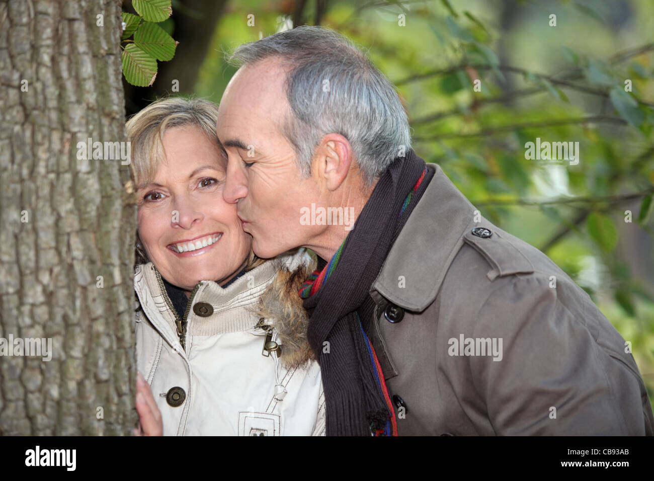Älterer Mann küssen seine Partner unter einem Baum Stockfoto