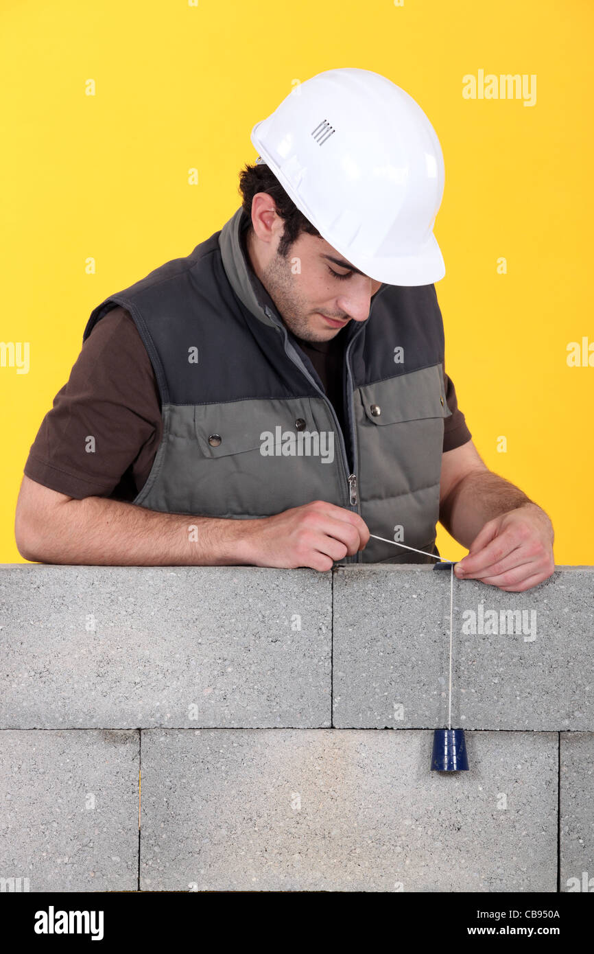 Ein Maurer mit einem Senklot, um seine Wand zu überprüfen. Stockfoto