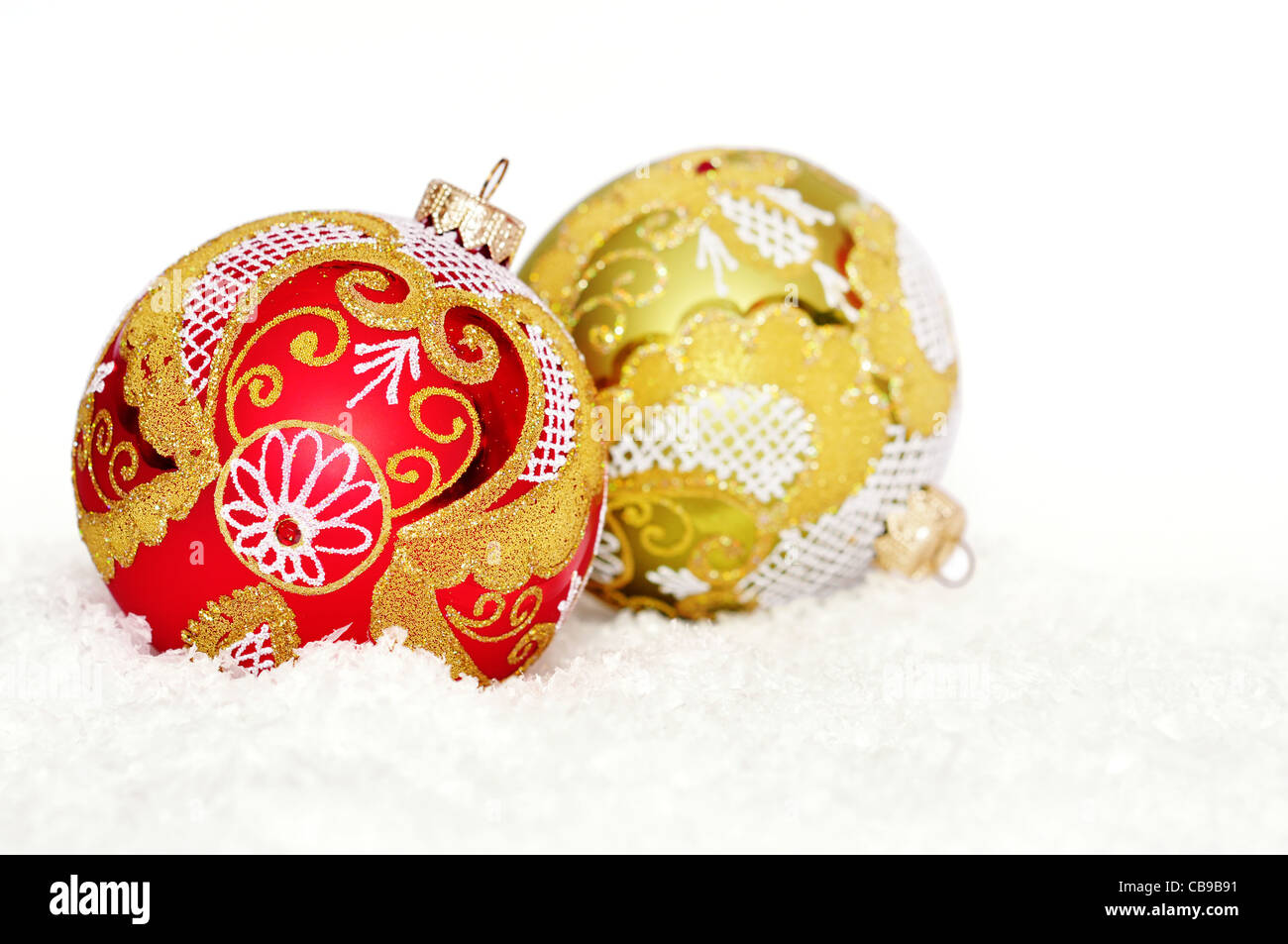 rote und goldene Weihnachtskugeln auf dem Schnee über weiß Stockfoto