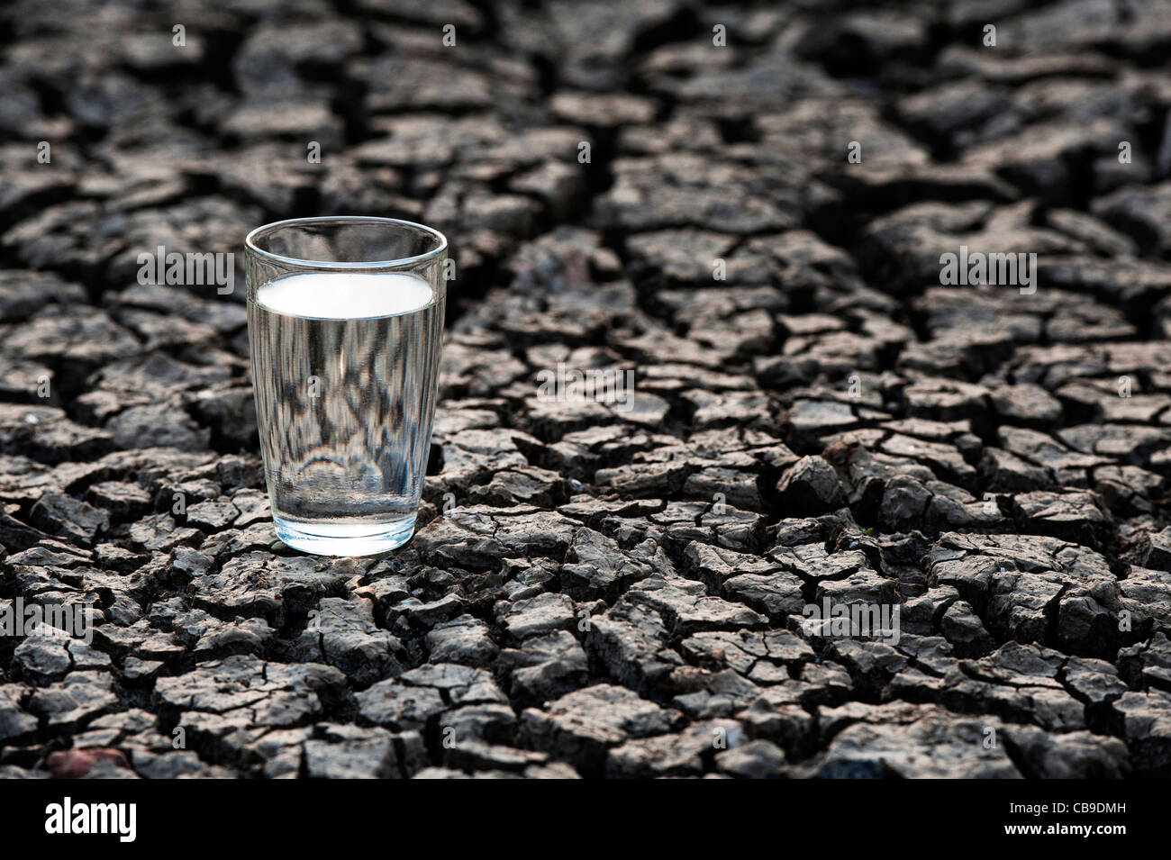 Glas Wasser auf die trockene Rissige Erde. Indien Stockfoto