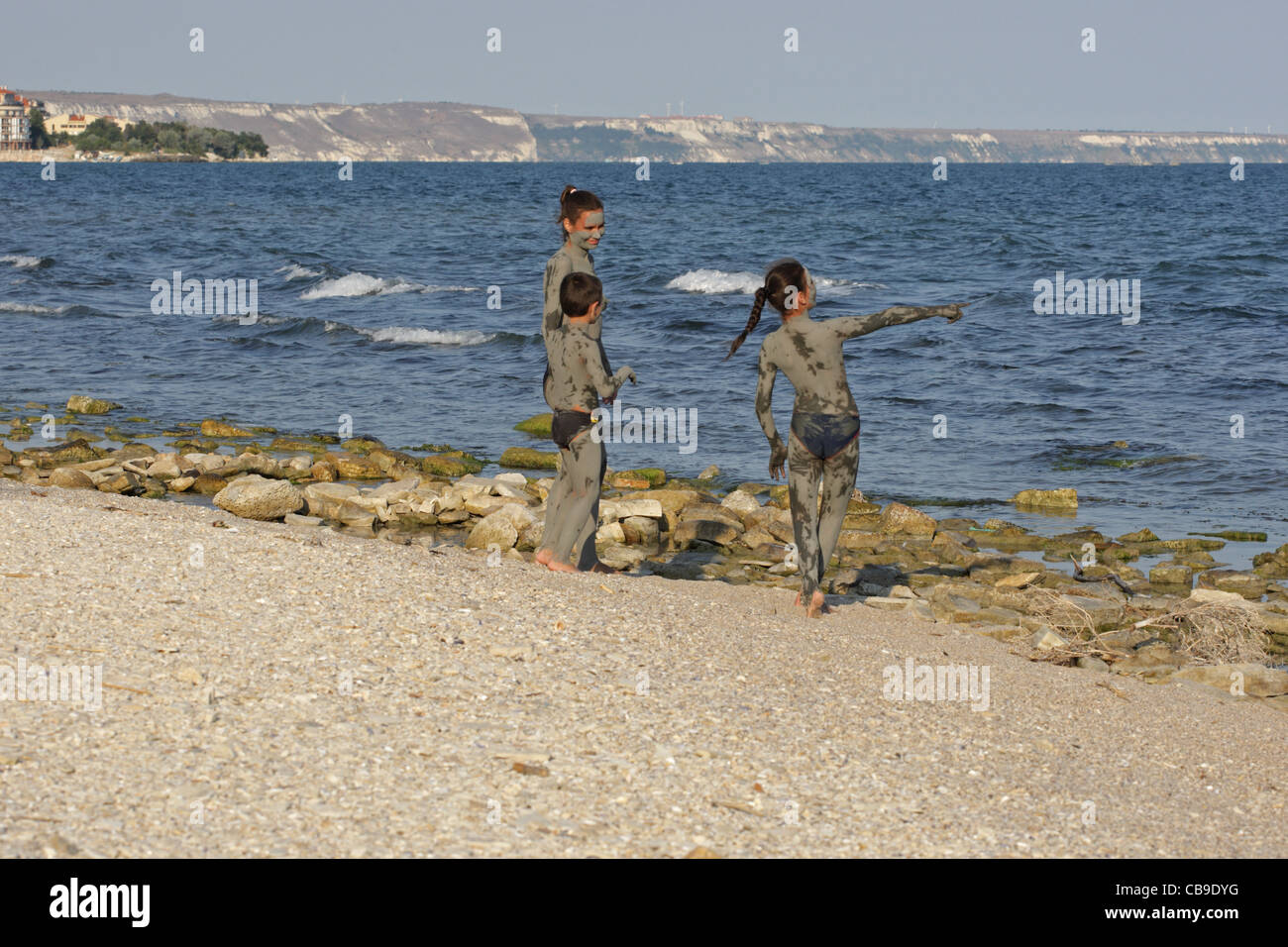 Kinder mit heilendem Schlamm bedeckt spielen am Strand, Tuzlata Resort in der Nähe von Stadt Balchik, Schwarzmeerküste, Bulgarien Stockfoto